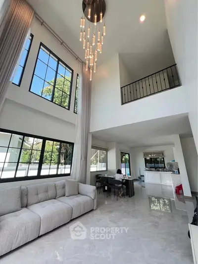 Luxurious modern living room with high ceilings and elegant chandelier in a spacious open-plan design.