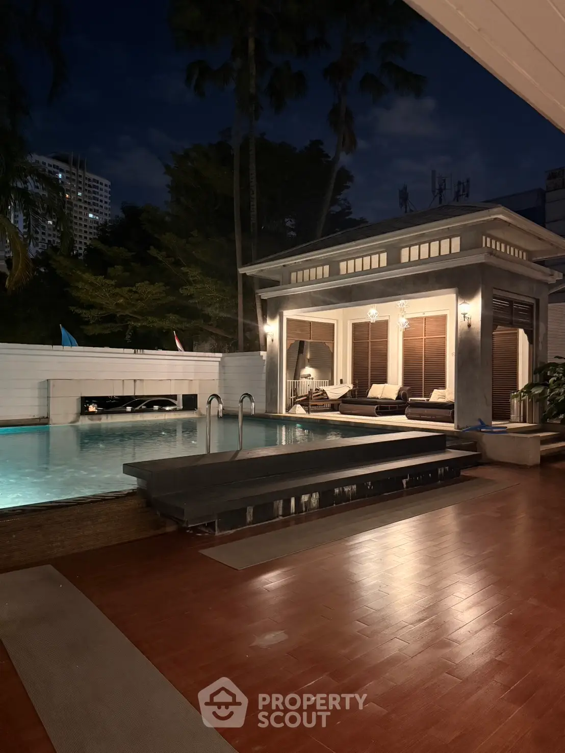 Luxurious poolside villa with elegant night lighting and modern design, perfect for relaxation and entertainment.