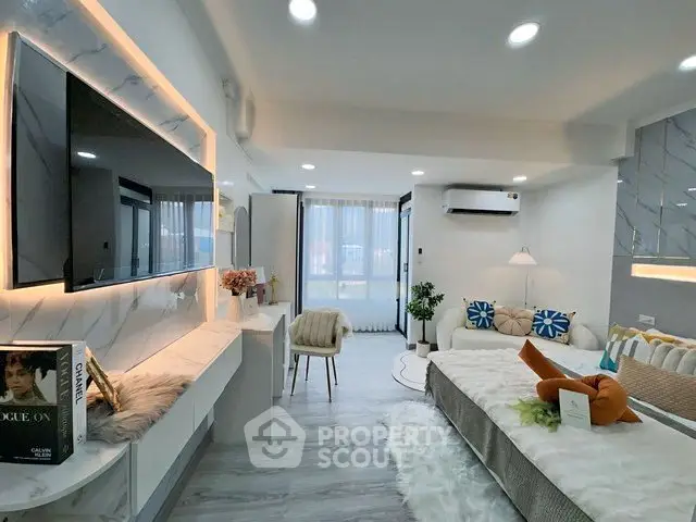 Modern living room with stylish decor, large TV, and cozy seating area in a bright apartment.