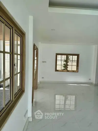 Spacious empty room with large windows and glossy tiled floors