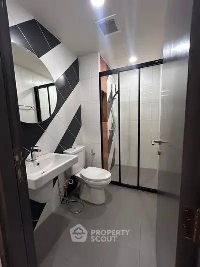 Modern bathroom with stylish black and white tiles and glass shower enclosure.