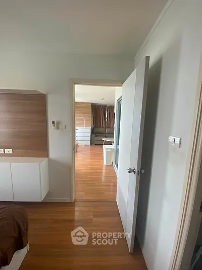 Spacious interior with wooden flooring and modern design, featuring a partially open door leading to a cozy living area.