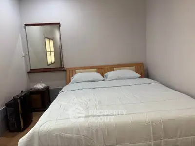 Cozy bedroom with double bed and wall mirror, perfect for restful nights.