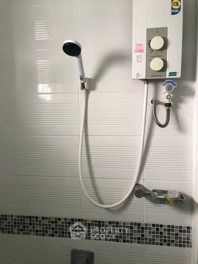 Modern bathroom with sleek shower head and water heater, featuring stylish tile accents.