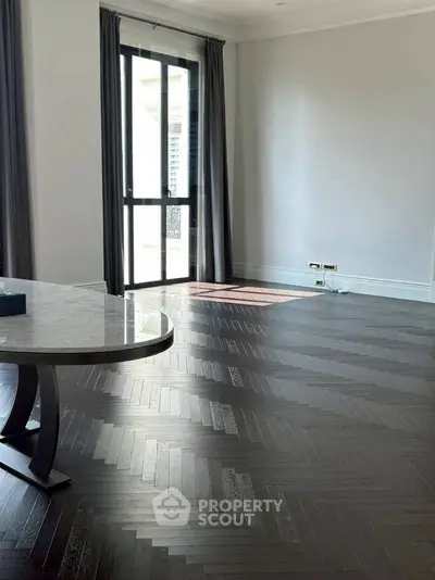 Spacious living room with elegant herringbone flooring and large window.