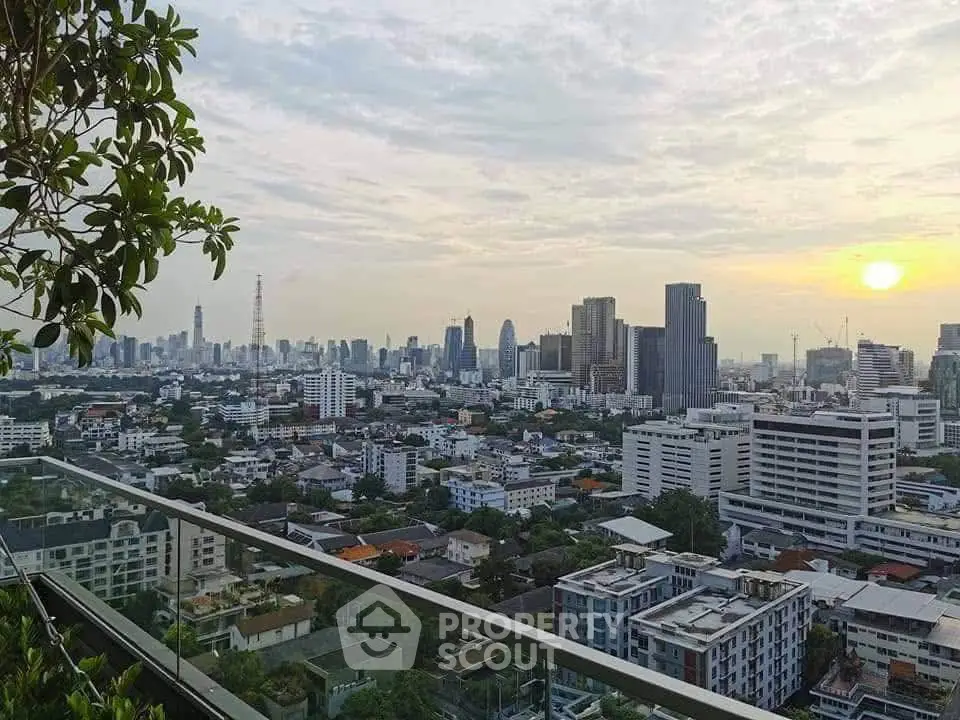 Stunning cityscape view from a high-rise balcony at sunset, showcasing urban skyline and lush greenery.