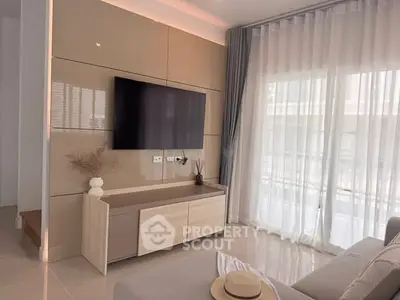 Modern living room with sleek TV setup and large windows for natural light.