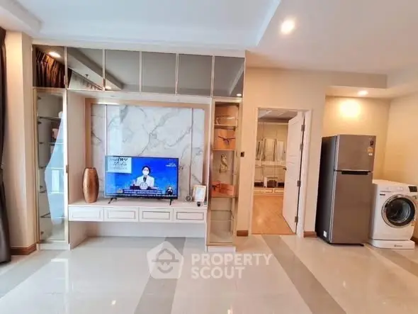 Modern living room with TV, fridge, and washing machine in stylish apartment.