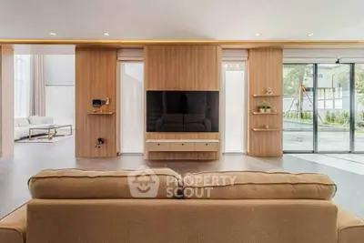 Spacious modern living room with large TV and sliding glass doors to garden.