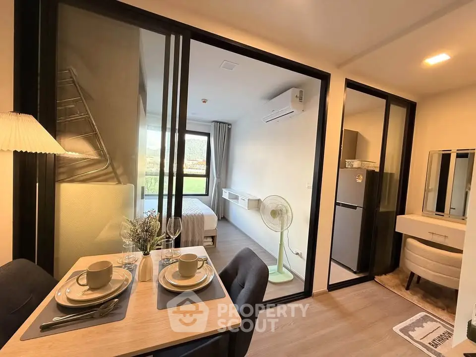 Modern apartment interior with dining area, bedroom, and kitchen featuring sleek design and natural light.