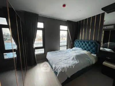 Luxurious bedroom with city view, featuring elegant decor and large windows.