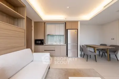 Modern open-plan living room with sleek kitchen and dining area, featuring stylish furniture and ambient lighting.