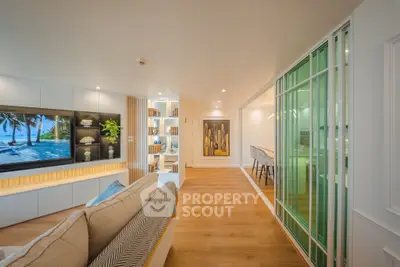 Modern living room with stylish decor and open layout, featuring a large TV and cozy seating area.