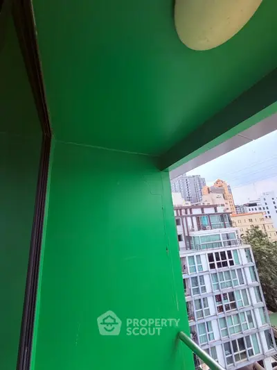 Modern urban balcony with vibrant green walls and city view