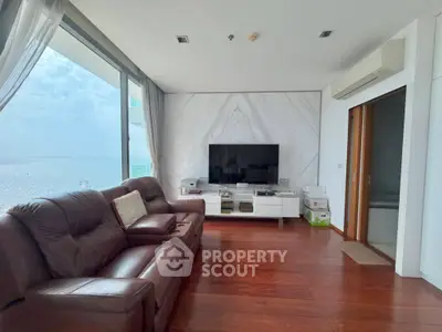 Luxurious living room with ocean view, leather sofas, and modern entertainment setup.