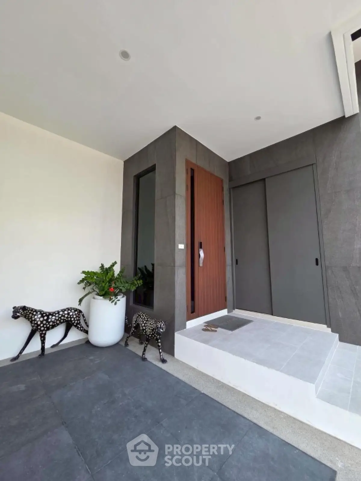 Modern entrance with sleek design and decorative elements, featuring stylish planters and artistic sculptures.