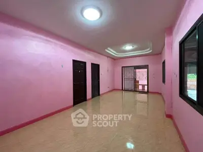 Spacious pink-walled room with glossy tiled floor and multiple doorways.