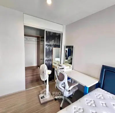 Modern bedroom with study area, featuring a sleek desk, ergonomic chair, and spacious closet.
