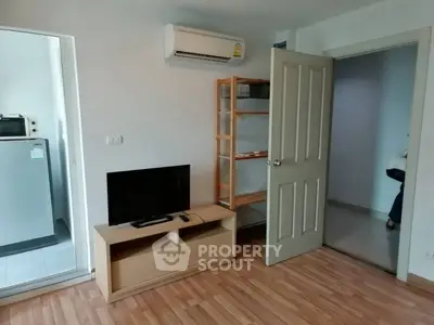 Cozy living room with wooden flooring, TV stand, and air conditioning unit.