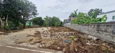 Vacant land plot with potential for development in a residential area, surrounded by greenery and neighboring houses.
