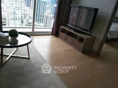 Modern living room with sleek TV stand and city view balcony in high-rise apartment.