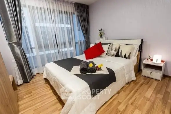 Modern bedroom with stylish decor and wooden flooring, featuring a cozy bed and elegant curtains.