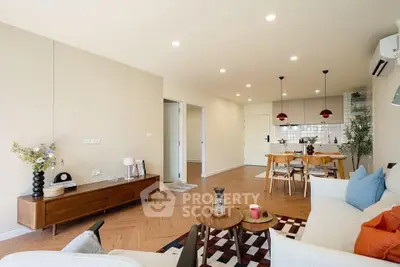 Spacious modern living room with open kitchen, stylish decor, and wooden flooring.