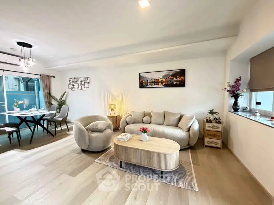 Spacious modern living room with elegant decor and dining area, featuring stylish furniture and natural light.