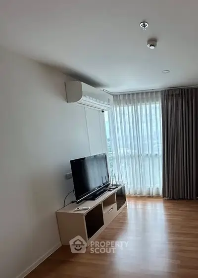 Modern living room with TV and large window offering natural light