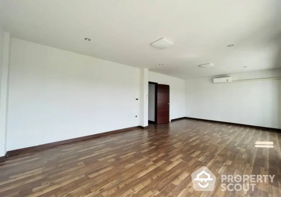 Spacious and elegant living room with polished hardwood floors and ample natural light, perfect for both relaxing and entertaining guests.