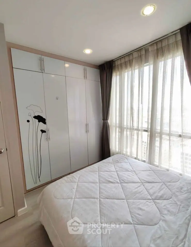 Bright bedroom with large window and stylish wardrobe in modern apartment