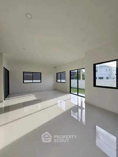 Spacious modern living room with large windows and glossy tile flooring.