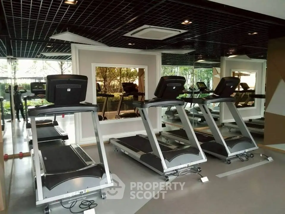 Modern gym with treadmills and mirrored walls in upscale residential building.