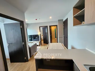 Modern open-plan living room with sleek kitchen and cozy dining area in a stylish apartment.