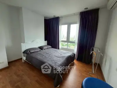 Spacious bedroom with large window and elegant dark curtains, offering a serene city view.