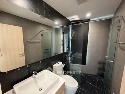Modern bathroom with sleek black marble tiles and glass shower enclosure