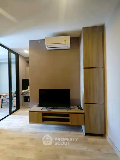 Modern living room with sleek TV setup and air conditioning in stylish apartment.