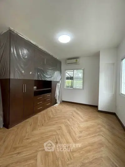 Spacious room with wooden flooring and built-in cabinets, perfect for modern living.