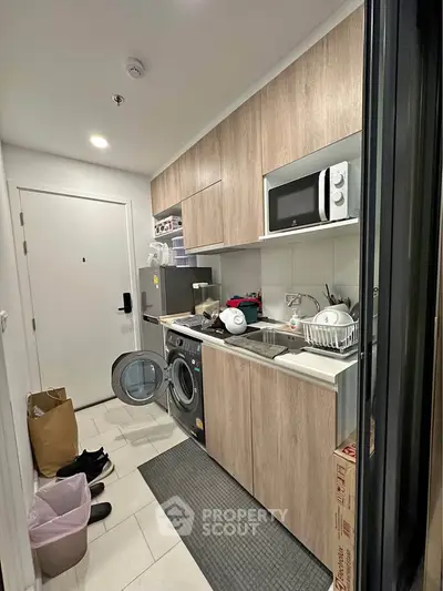 Compact kitchen with modern appliances and washing machine in cozy apartment
