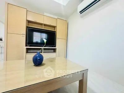 Modern living room with sleek wooden furniture and air conditioning, featuring a stylish blue vase centerpiece.