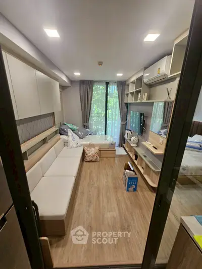 Modern living room with sleek design and large windows overlooking greenery, featuring cozy seating and stylish decor.