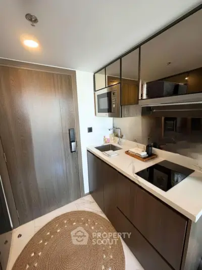 Modern compact kitchen with sleek cabinetry and built-in appliances in a stylish apartment.