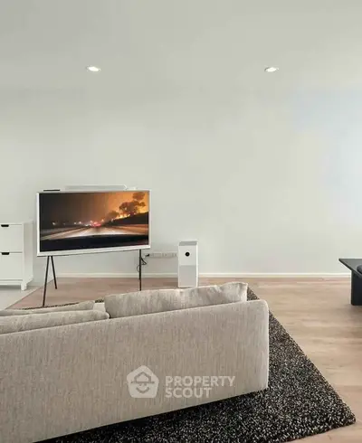 Modern living room with sleek TV setup and stylish furniture on wooden flooring.