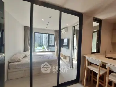 Modern apartment with bedroom and kitchen, featuring large windows and sleek design.