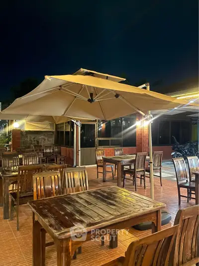 Charming outdoor dining area with wooden tables and large umbrellas, perfect for evening gatherings.