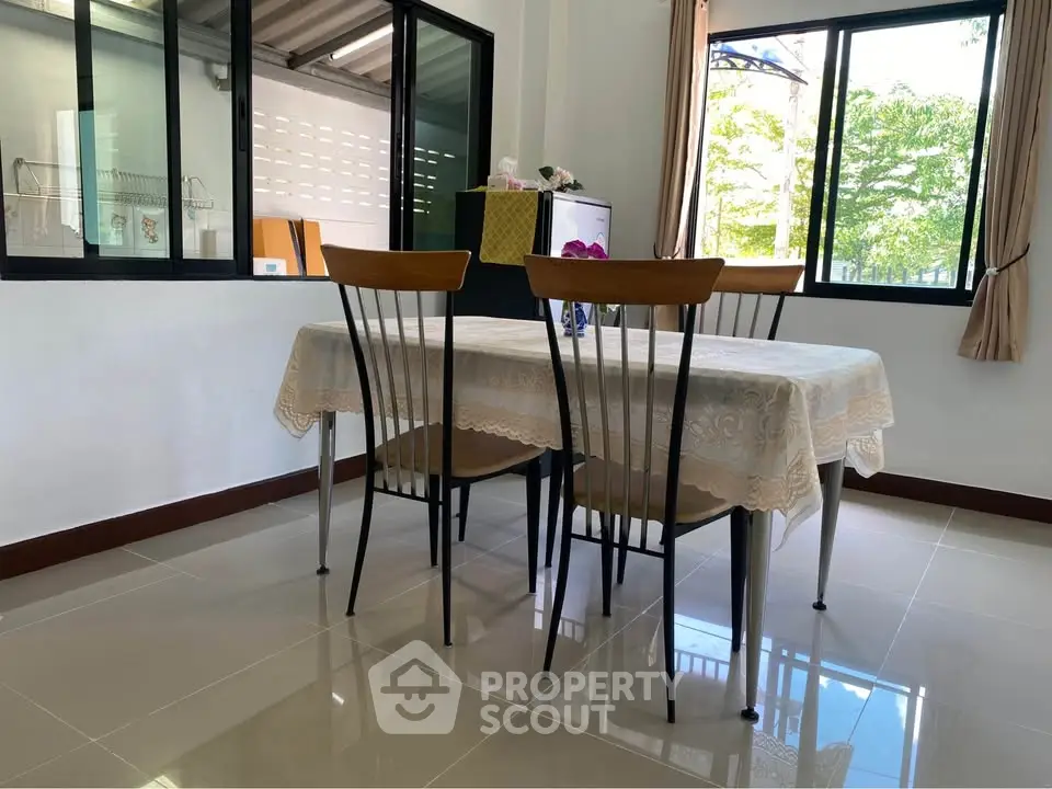 Bright dining area with modern table and chairs, large windows, and tiled flooring.
