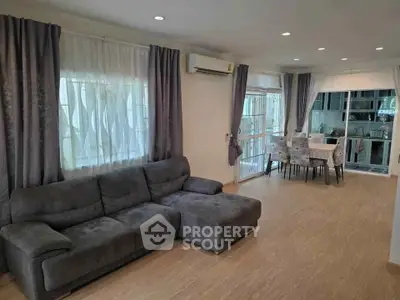Spacious living room with modern decor and open layout leading to dining area and kitchen.