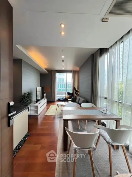 Spacious modern living room with large windows and stylish furniture in a high-rise apartment.