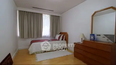 Cozy bedroom with single bed, dresser, and large window with curtains.