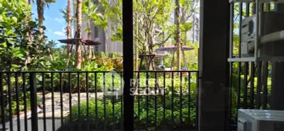 Lush garden view from a modern apartment balcony with vibrant greenery and outdoor seating.